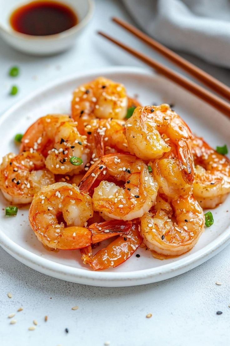 a white plate topped with shrimp next to chopsticks