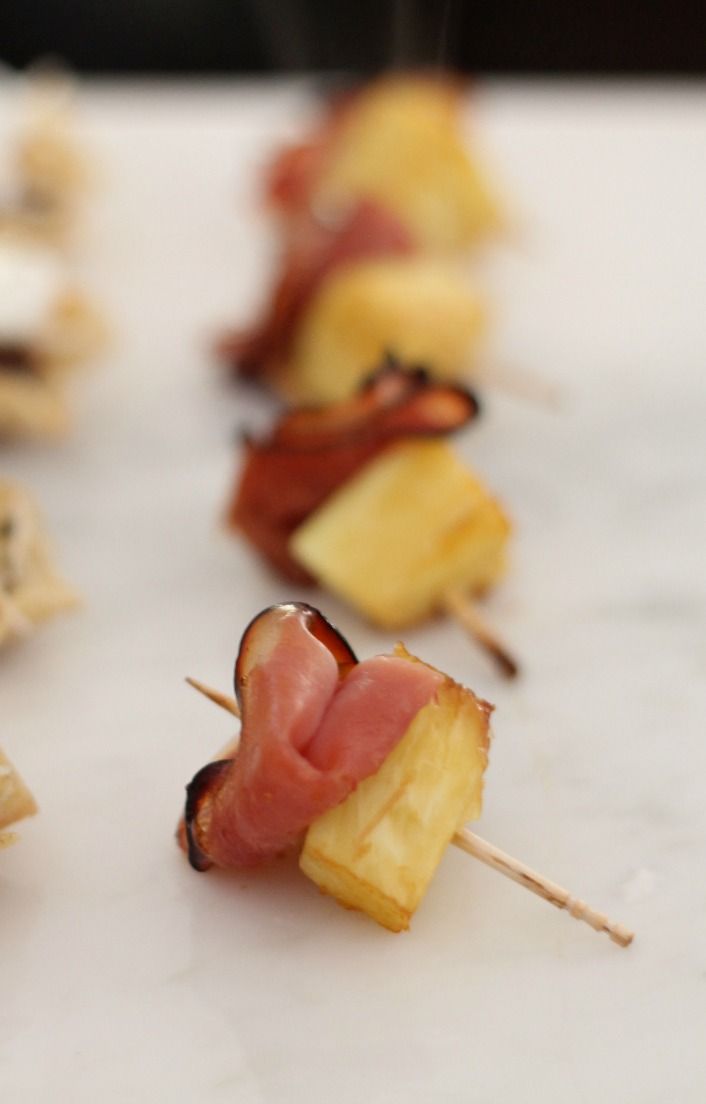 several skewered food items on sticks with bacon and pineapple