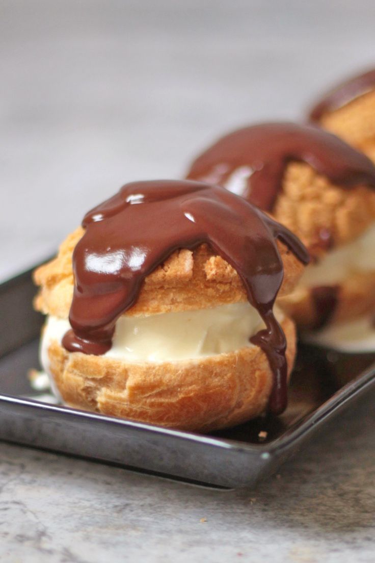 two ice cream sandwiches with chocolate drizzled on them sitting on a black plate