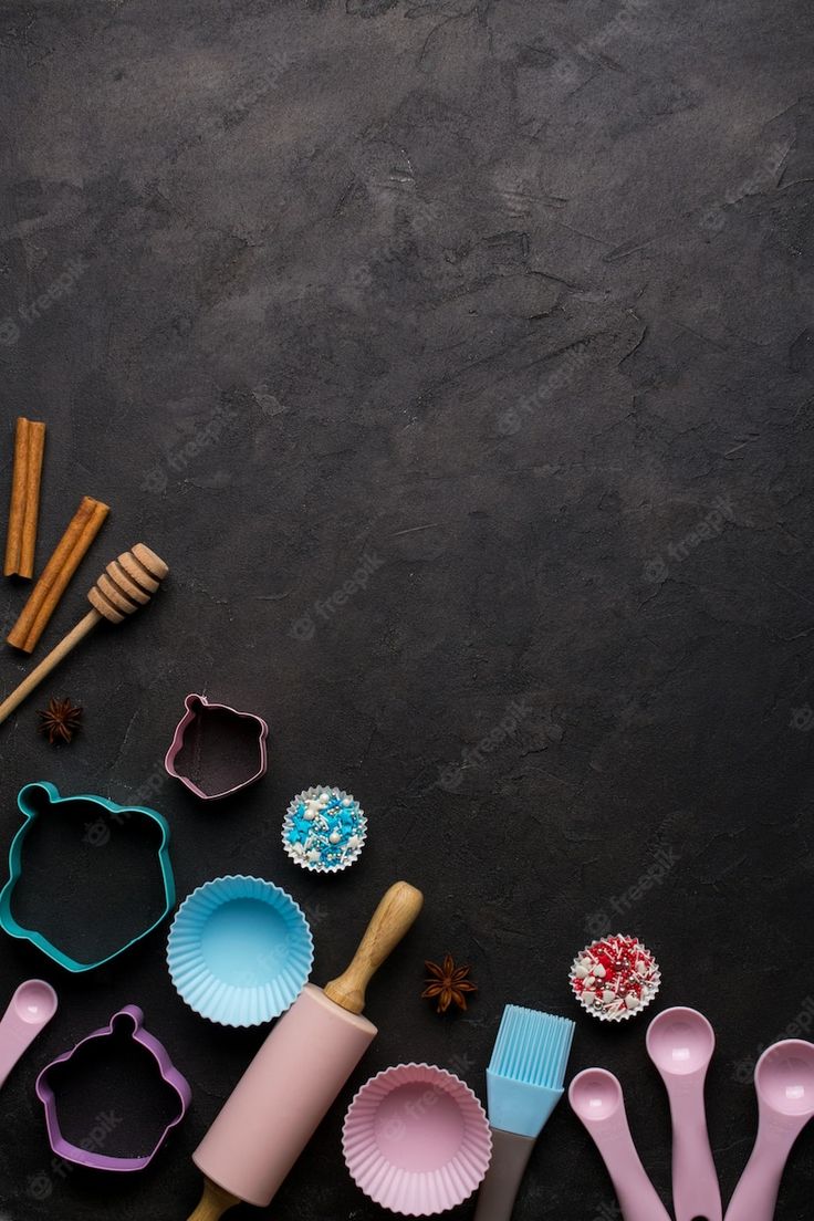 various baking utensils and cookie cutters laid out on a black surface with space for text