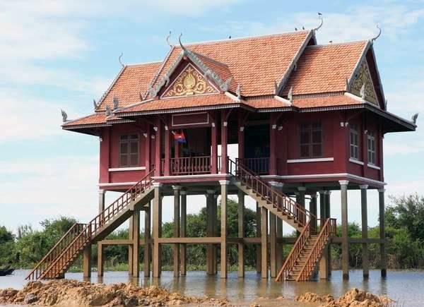 an old house on stilts in the water with stairs leading up to it's roof