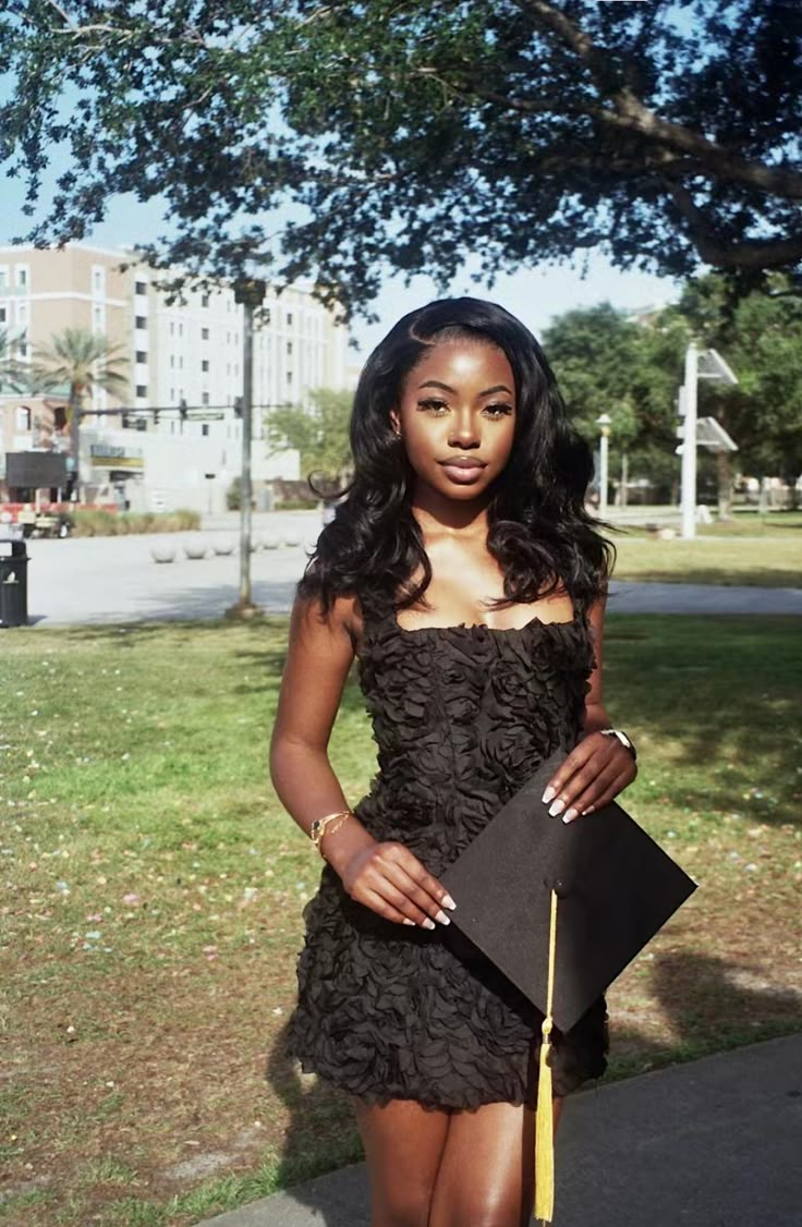 a woman in a short black dress is holding a book and posing for the camera