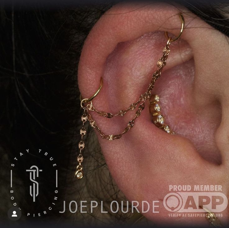 a close up of a person's ear with gold chains attached to the ear