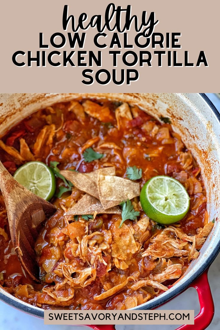 a red pot filled with chicken tortilla soup and topped with lime wedges