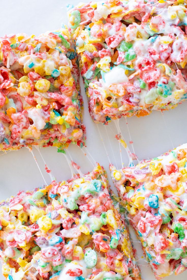 colorful rice krispy kreme treats are arranged on a white surface with sprinkles