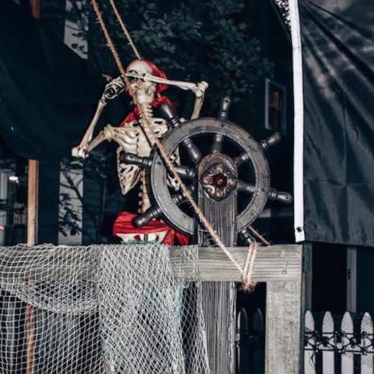 a skeleton dressed up as a pirate with a ship's wheel on the deck