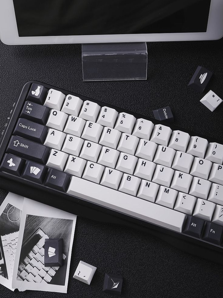 a computer keyboard sitting on top of a desk next to a mouse and some pictures