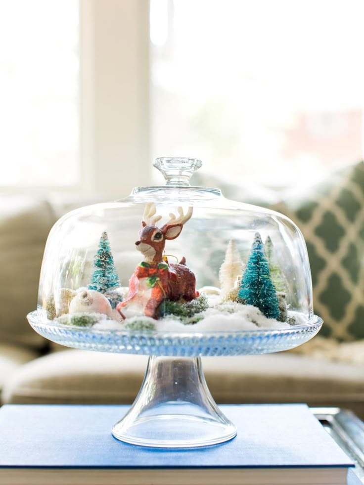 a glass cake plate with a deer under it on top of a table next to a couch