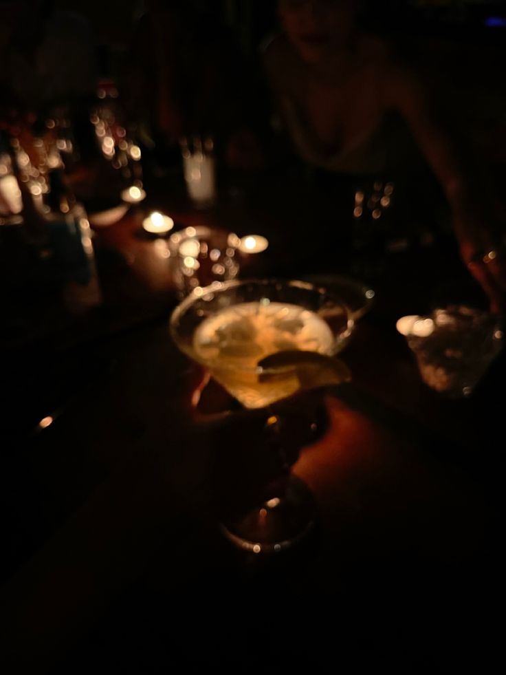 a person sitting at a table with some drinks in front of them and candles on the table