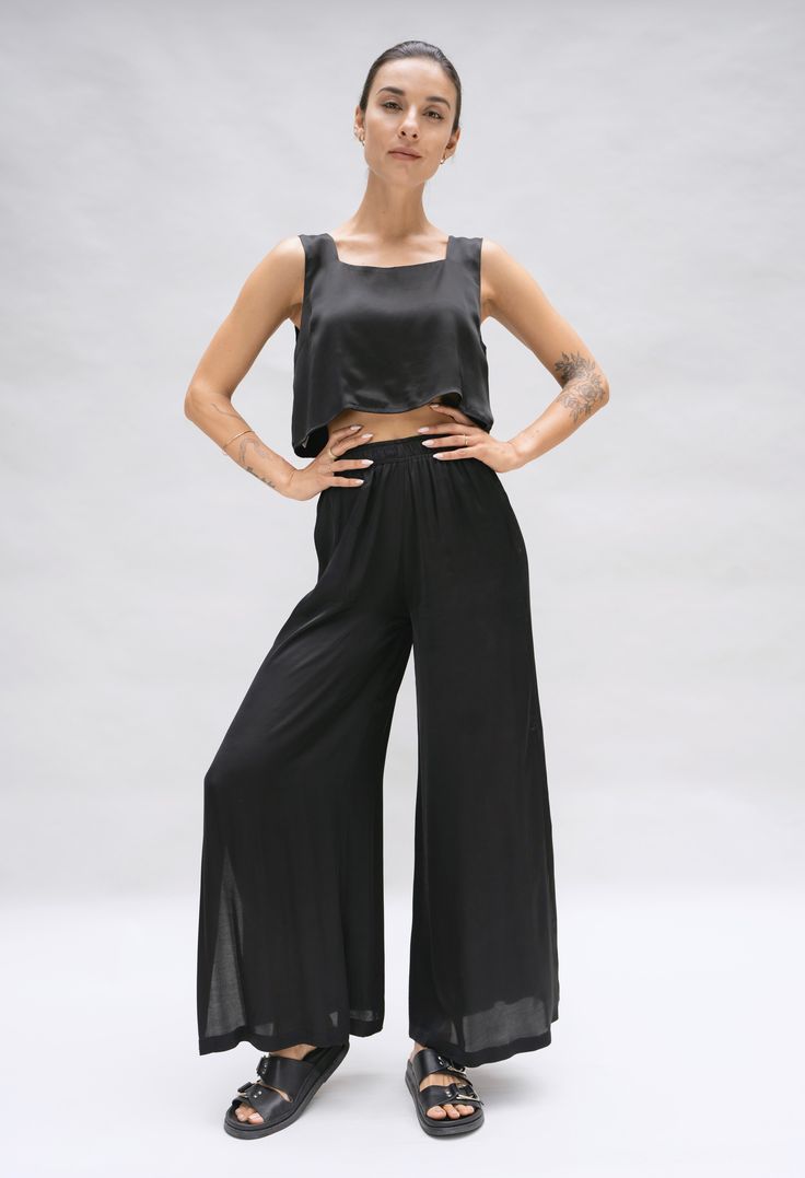 Model is posing in a studio. She is wearing a black crop top and matching wide leg pant in a black silky fabric by Fauna The Label. Versatile Wide Leg Viscose Pants With Elastic Waistband, Versatile Viscose Wide Leg Pants With Elastic Waistband, Solid Wide-leg Viscose Pants, Solid Viscose Wide-leg Pants, Ankle-length Solid Viscose Wide Leg Pants, Versatile Ankle-length Viscose Wide Leg Pants, Versatile Straight Leg Viscose Bottoms, Versatile High-waisted Viscose Pants, Viscose Stretch Wide Leg Bottoms