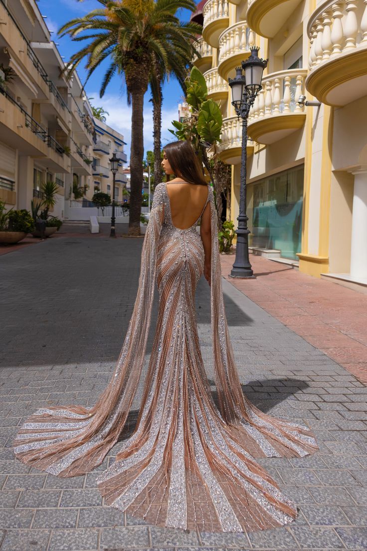 the back of a woman's wedding dress in front of palm trees and buildings