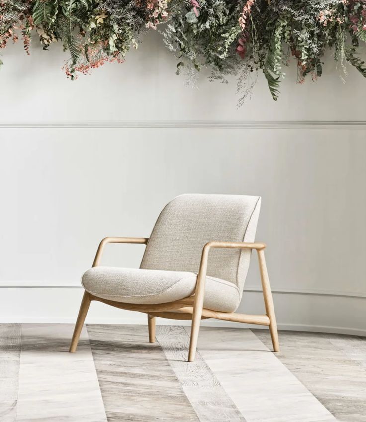 a chair sitting in front of a wall with flowers hanging from it's sides