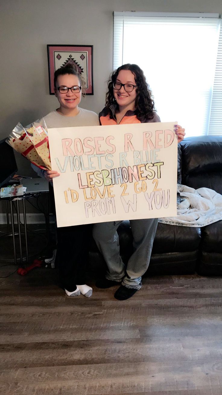 two people holding up a sign that says roses are red violets are the best