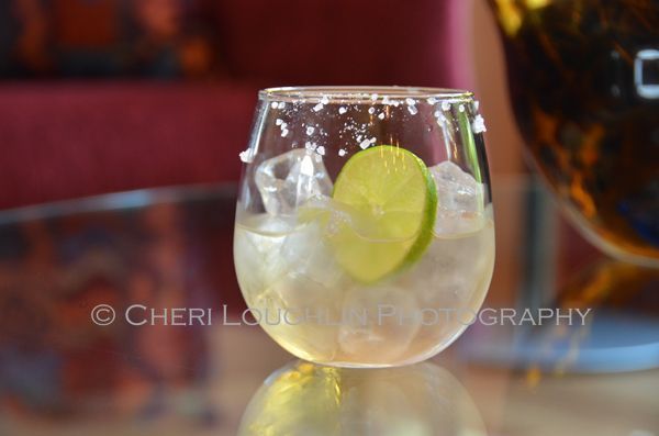 a glass filled with ice and lime sitting on top of a table