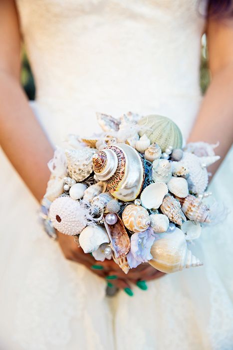 a bride holding a wedding bouquet with seashells