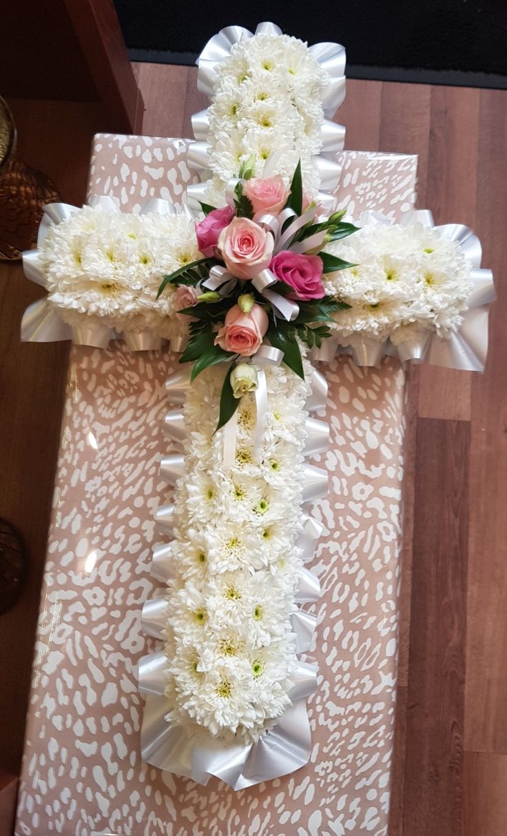 a cross decorated with white and pink flowers