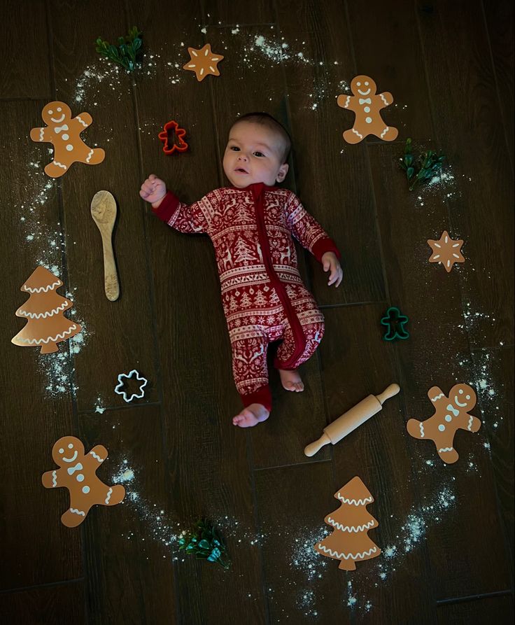 a baby is laying on the floor surrounded by gingerbreads and other decorations,