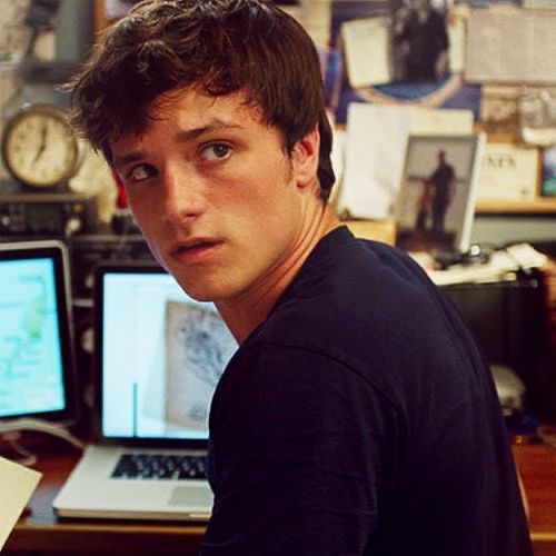 a young man sitting at a desk in front of two computer monitors