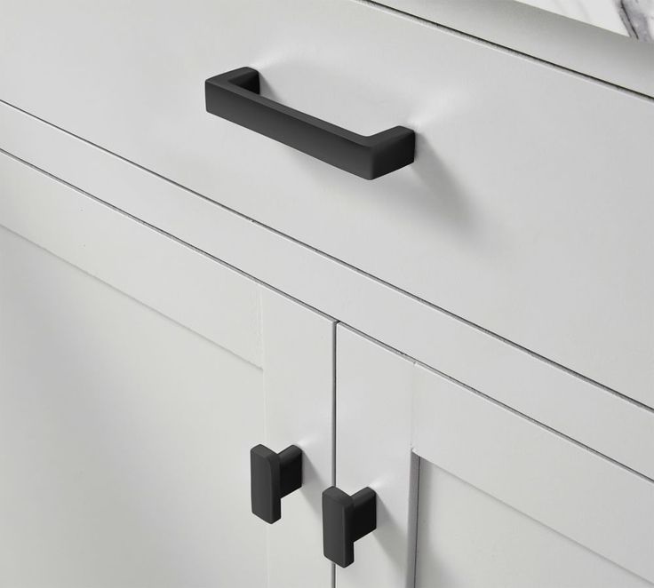 a white dresser with black handles and knobs