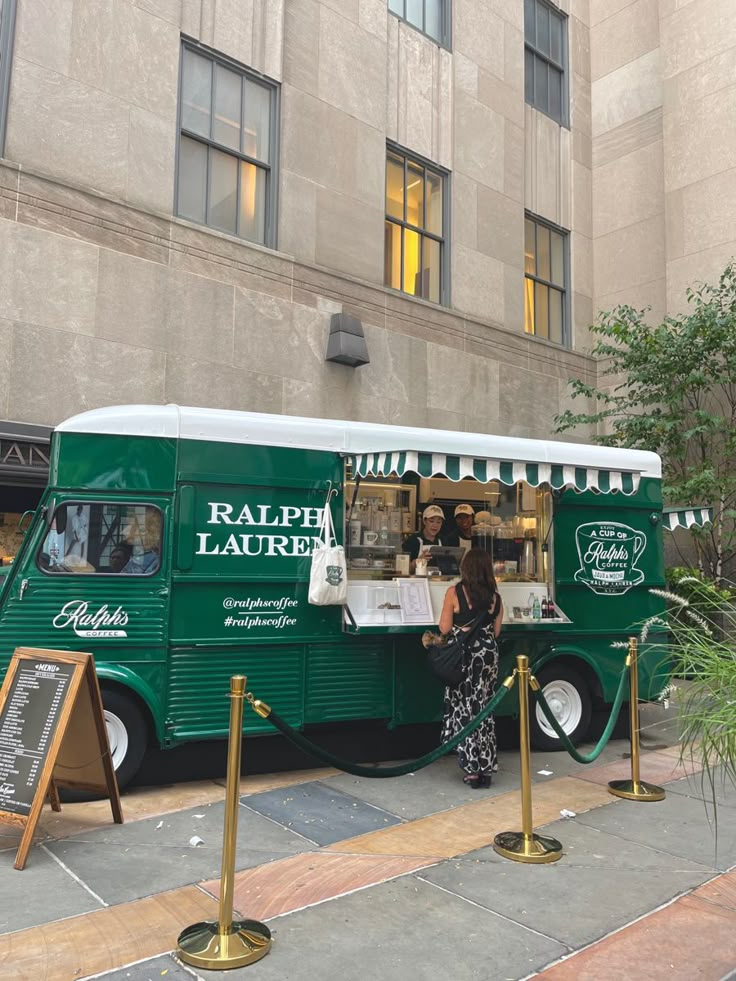 a green food truck parked in front of a tall building