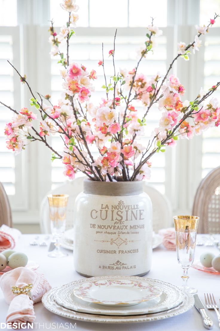 the table is set with pink flowers in a mason jar and place setting for two