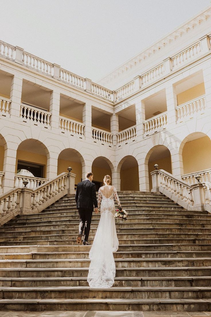 the bride and groom are walking down the stairs at their wedding reception in front of an elegant building