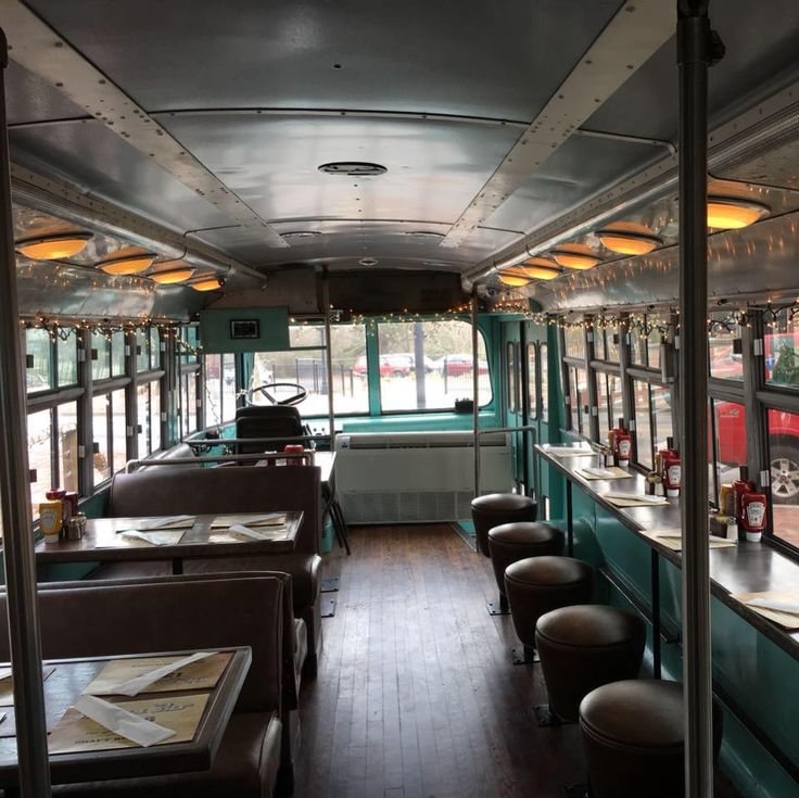 the inside of a bus with tables and chairs on each side, along with lots of windows