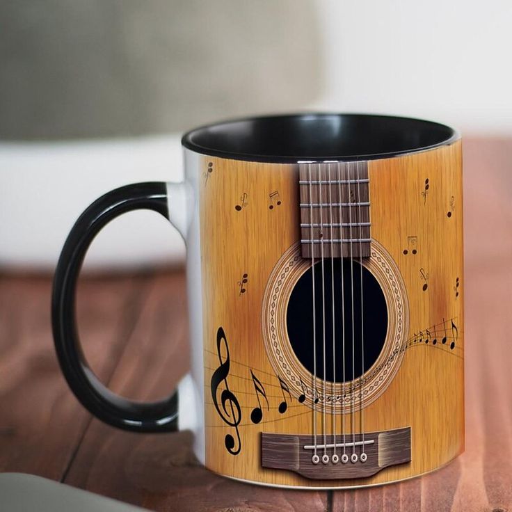 a coffee mug with a guitar design on the front and sides, sitting on a wooden table