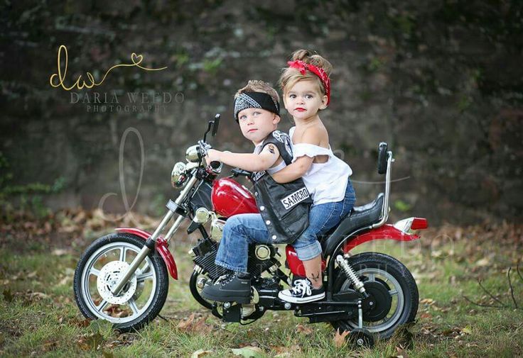 two children are sitting on a red motorcycle