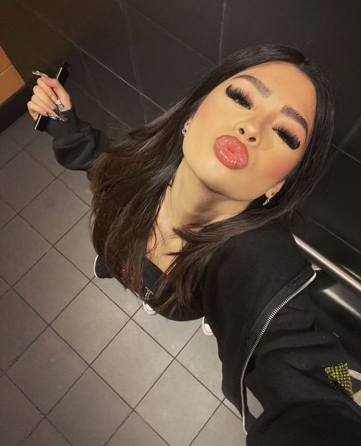 a woman taking a selfie in the bathroom with her cell phone up to her ear