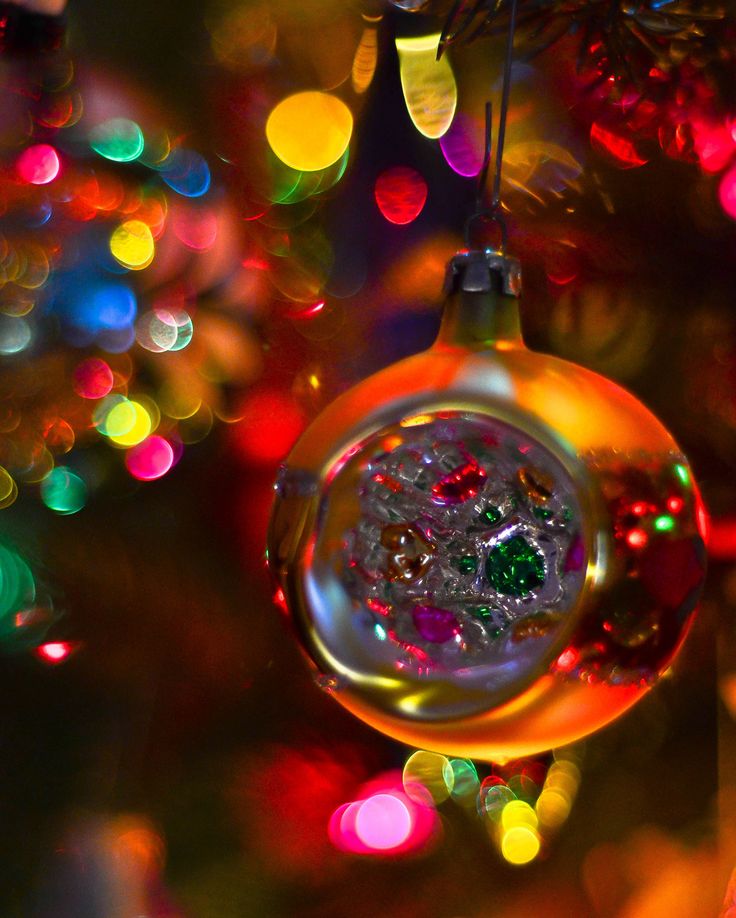 an ornament hanging from a christmas tree with colorful lights in the back ground