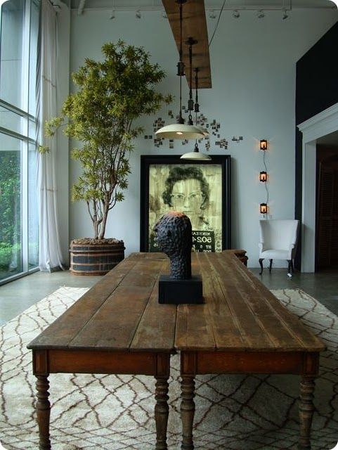 a living room with a large wooden table in front of a painting on the wall