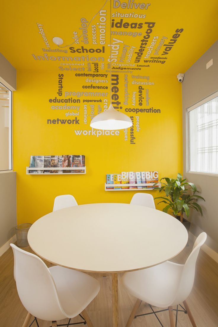 a dining room table with white chairs and a yellow wall in the background that has words written all over it