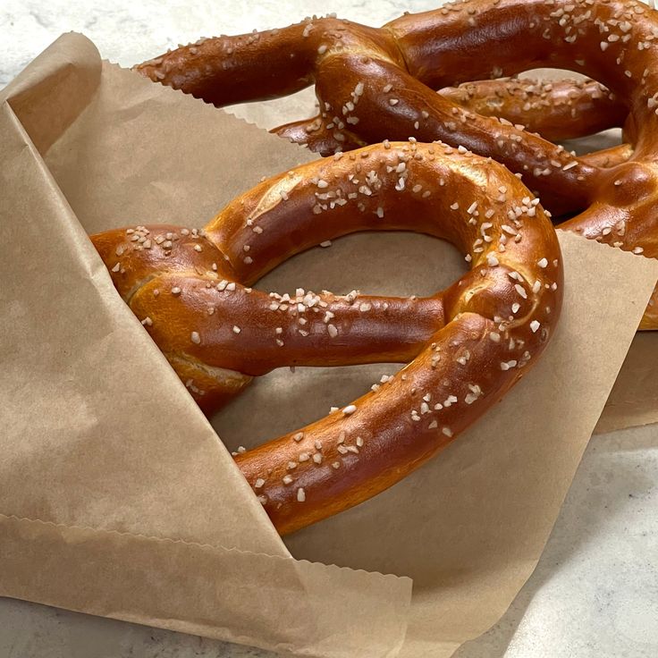 two large pretzels sitting on top of brown paper bag bags filled with sesame seeds