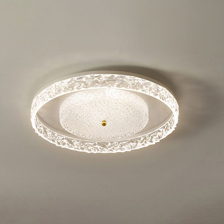 a white ceiling light with an intricate design on the top and bottom part is lit up