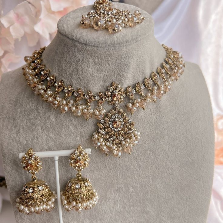 a necklace and earring set on display in a shop window with flowers behind it