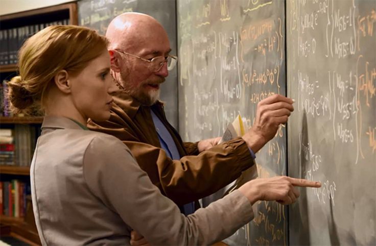 a man and woman writing on a blackboard