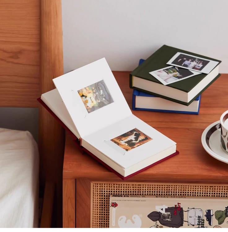 an open book sitting on top of a wooden table next to a cup and saucer