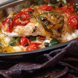 a pan filled with fish and vegetables next to tortilla chips