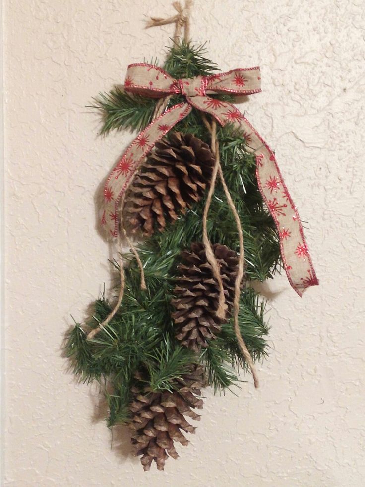 a pine cone hanging from a wall with a bow on it's head and two cones attached to the front