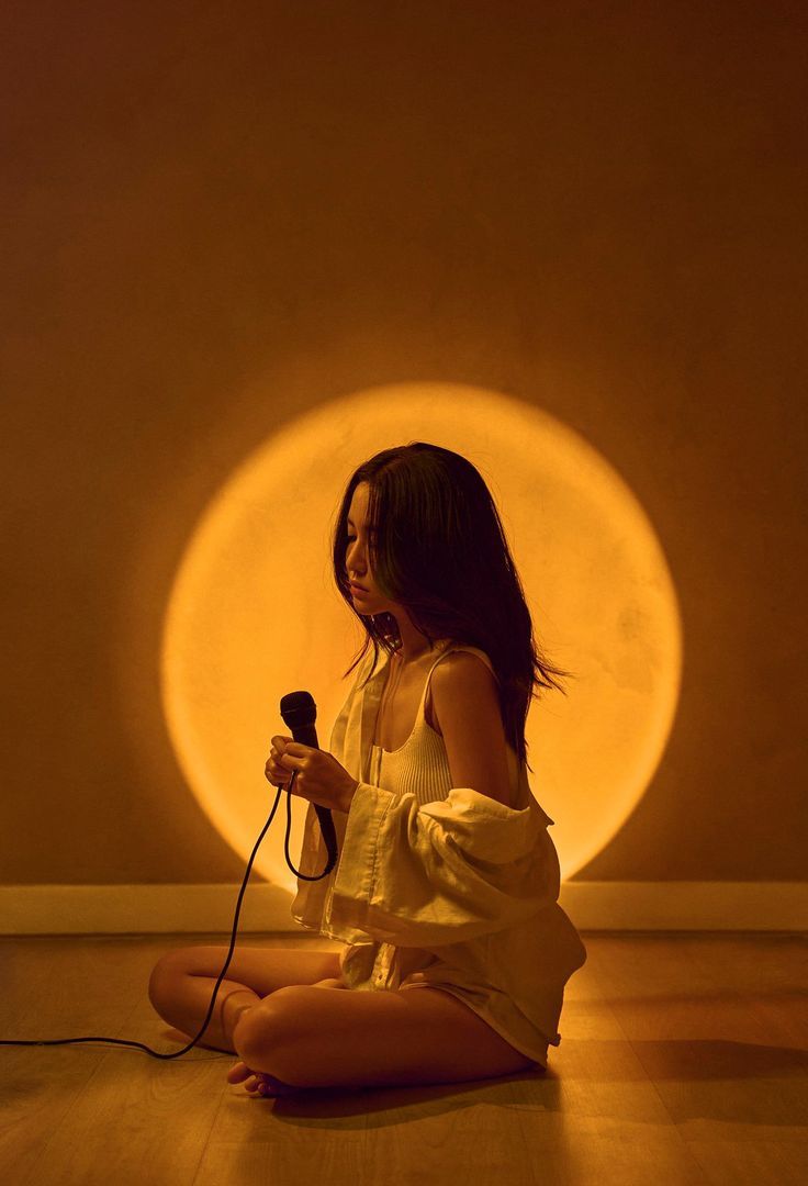 a woman sitting on the floor holding a microphone