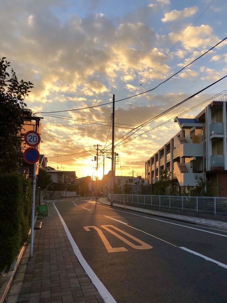 the sun is setting over an empty street