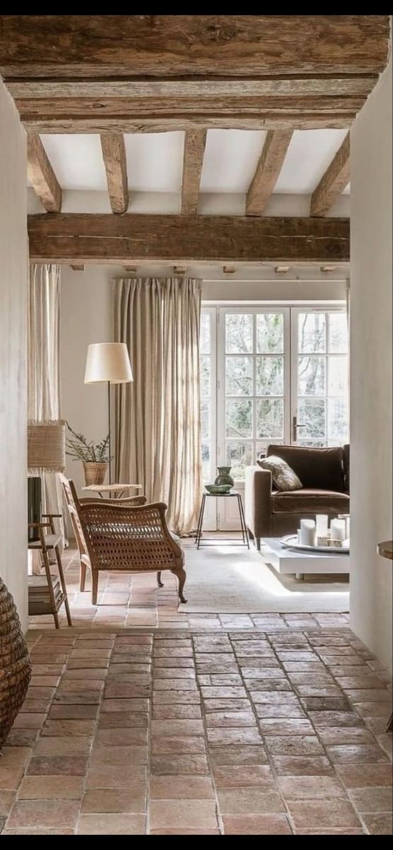 a living room filled with furniture and a stone floor covered in lots of light brown curtains