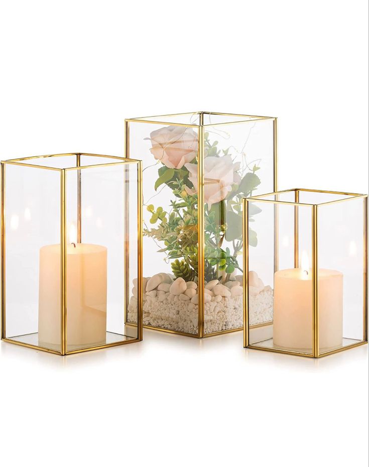 three glass vases with flowers and rocks in them, one is filled with sand