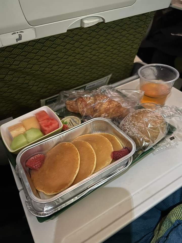 an airplane tray with pancakes, fruit and other food items on top of the tray