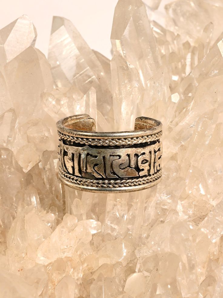 This adjustable ring is hand crafted by local artists of Katmandu Nepal. It features the well known and beloved Tibetan holy mantra Om Mani Padme Hum artfully carved around the band, with a delicate ropelike design around both sides. The ring can be gently pressed together to adjust to whichever finger on which you choose to wear it. Wear it for protection in all directions and to bring love and spiritual harmony into your journey. Made of sterling silver, it is attractive and adjustable. Measur Katmandu Nepal, Om Mane Padme Hum, Om Mani Padme Hum, Ancient Wisdom, Local Artists, Adjustable Ring, Adjustable Rings, Mantra, Nepal