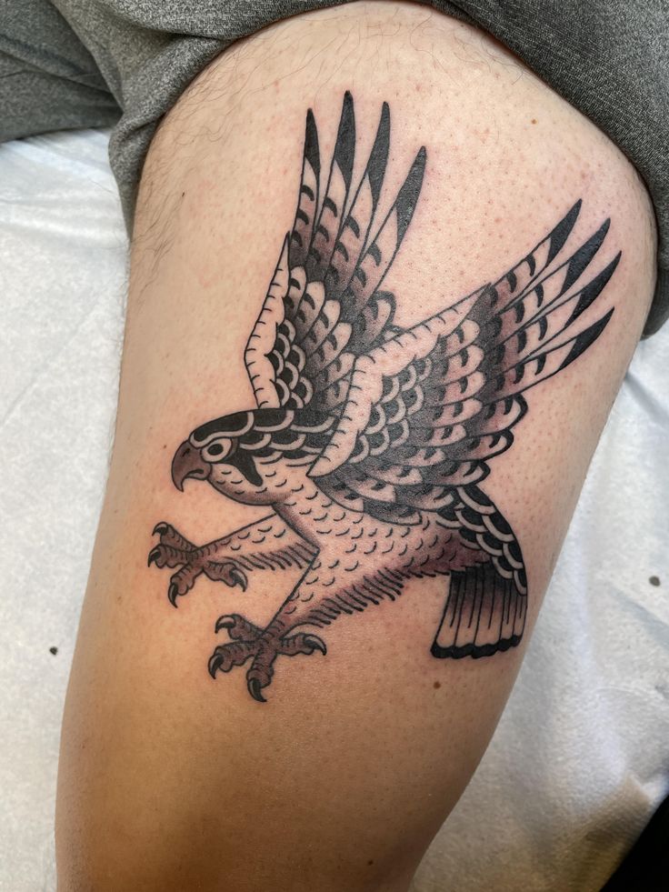 an eagle tattoo on the leg of a person's leg, with black and grey ink