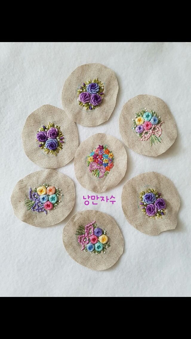 six embroidered flowers on linen coasters with japanese writing in the middle and english characters below