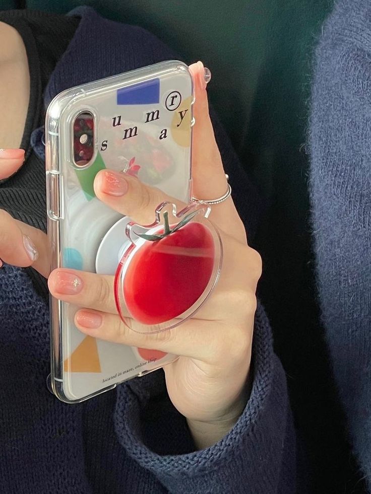 a woman holding up her phone case with an apple inside