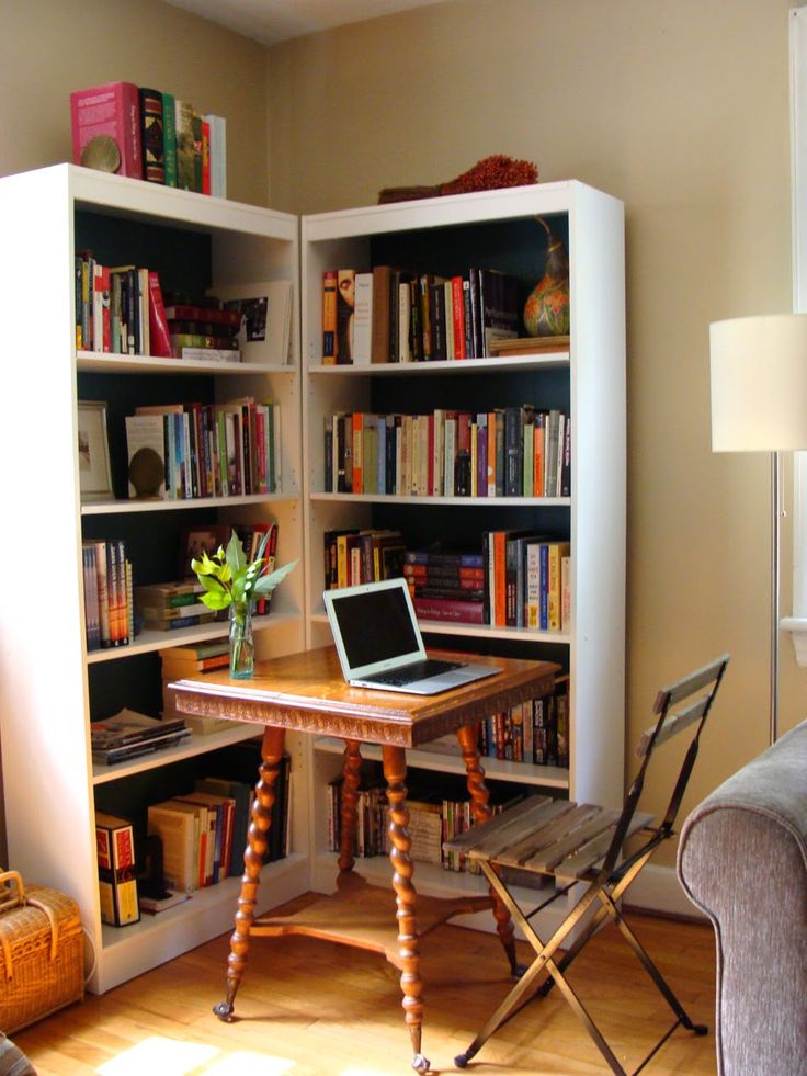 a laptop computer sitting on top of a wooden table in front of a book shelf